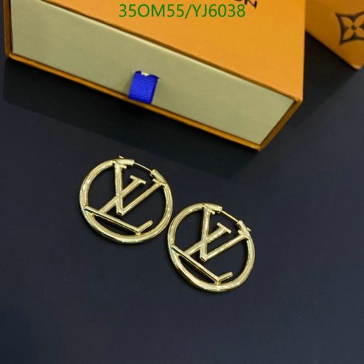 Designer logo earrings on dark surface near box.