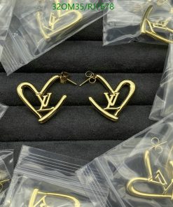 Gold designer logo earrings on black display.