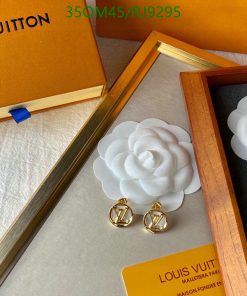 White flower brooch and gold earrings on display box.