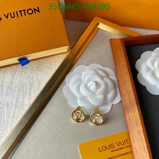 White flower brooch and gold earrings on display box.