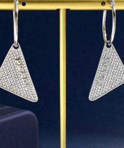 Diamond triangle earrings on gold stand.