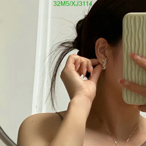 Woman adjusting earring while taking a mirror selfie.