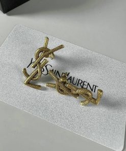 Gold designer logo earrings on white background.