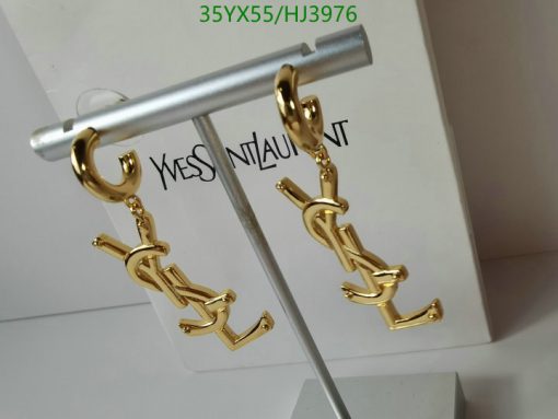 Gold designer logo earrings on display stand.