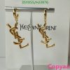 Gold designer logo earrings on display stand.