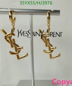 Gold designer logo earrings on display stand.