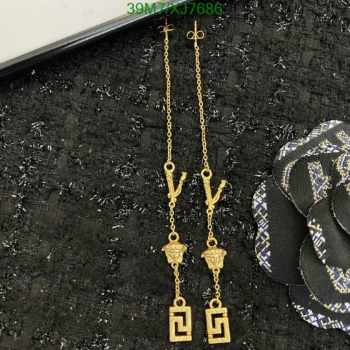 Gold drop earrings with geometric design on black fabric.