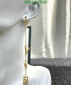 Gold dangle earring on mannequin's ear.