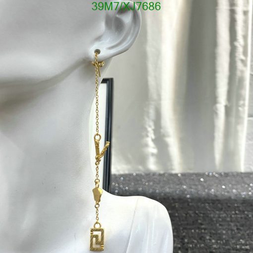 Gold dangle earring on mannequin's ear.