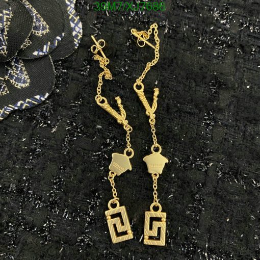 Gold designer dangle earrings on textured background.