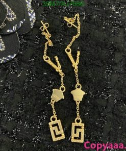 Gold pendant earrings on black textured background.