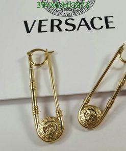 Gold safety-pin style earrings on branded backdrop.