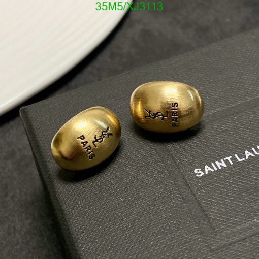 Gold designer earrings on black packaging.