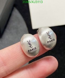 Silver designer logo earrings held between fingers.