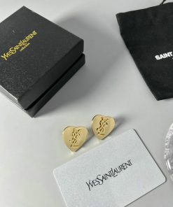 Designer earrings with brand packaging on table.