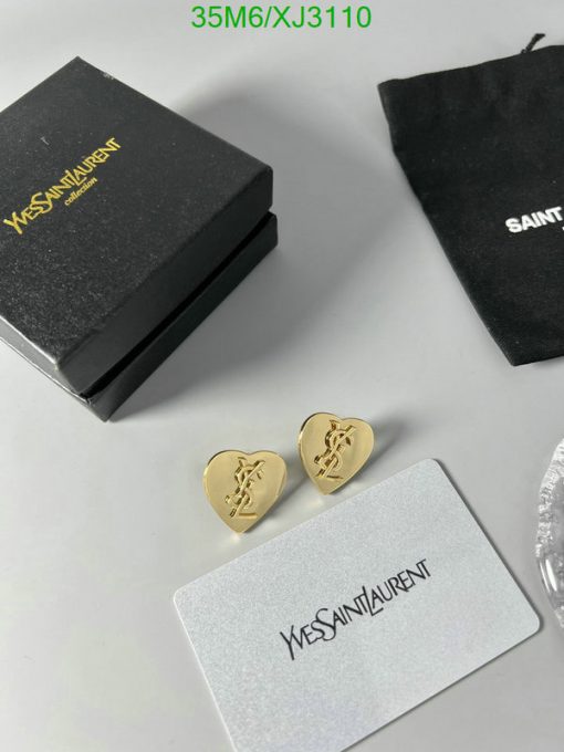 Designer earrings with brand packaging on table.