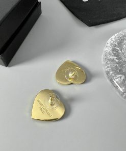 Gold Saint Laurent guitar pick earrings on table