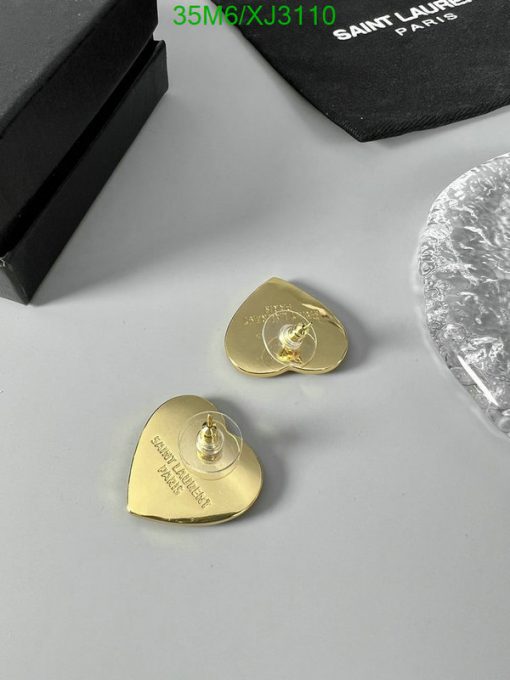 Gold Saint Laurent guitar pick earrings on table