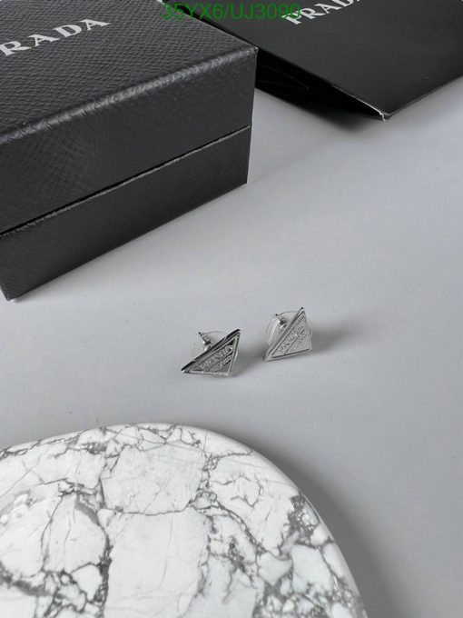 Prada cufflinks with box on marble surface.