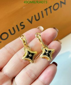 Gold star-shaped earrings held near branded box.