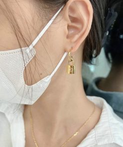 Woman wearing unique lock-shaped gold earring.