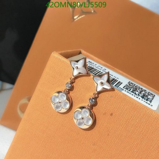 Star and flower motif gold earrings on orange box.