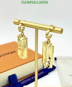 Gold designer logo earrings displayed on stand.