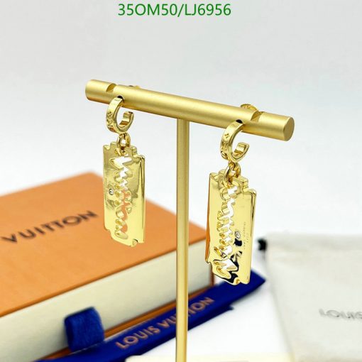 Gold designer logo earrings displayed on stand.