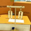 Louis Vuitton gold-tone razor blade earrings display on stand.