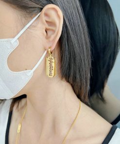 Woman wearing a mask and gold razor blade earring.