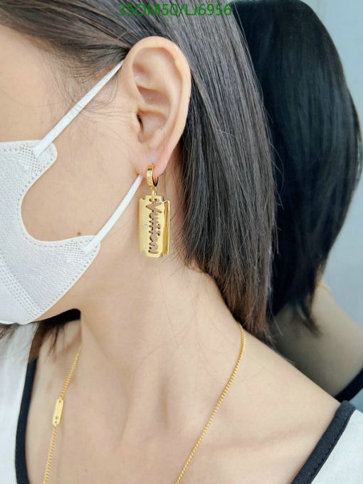 Woman wearing a mask and gold razor blade earring.