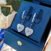 Designer heart-shaped diamond earrings in box.