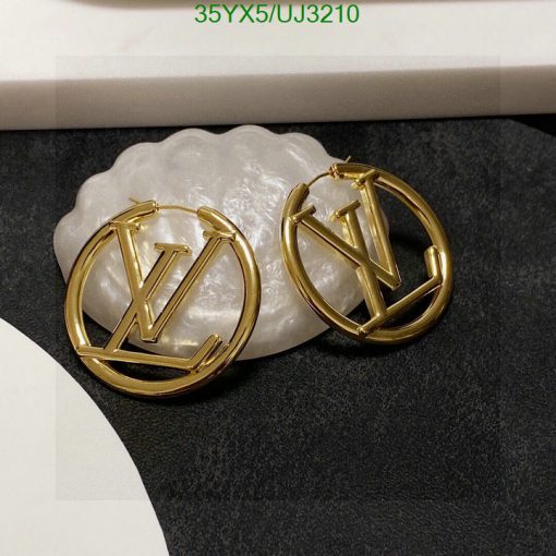 Gold designer logo earrings on white stand.