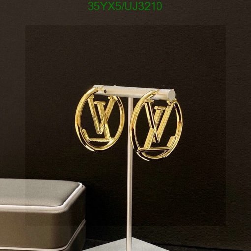 Gold designer logo earrings on display stand.