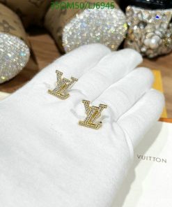 Gold initial earrings on white gloved hand.