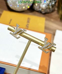 Gold designer logo hairpin with crystals on display.