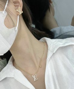 Woman wearing designer initial earrings and necklace.