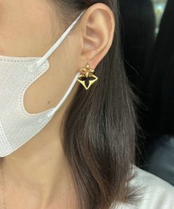 Woman wearing gold star-shaped earring and face mask.