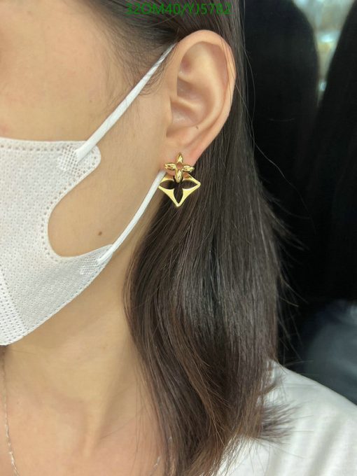 Woman wearing gold star-shaped earring and face mask.