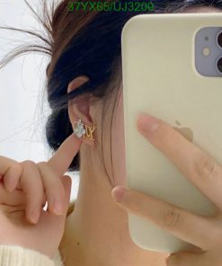 Person showing earring while taking selfie with phone.