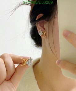 Woman displaying designer monogram earrings.