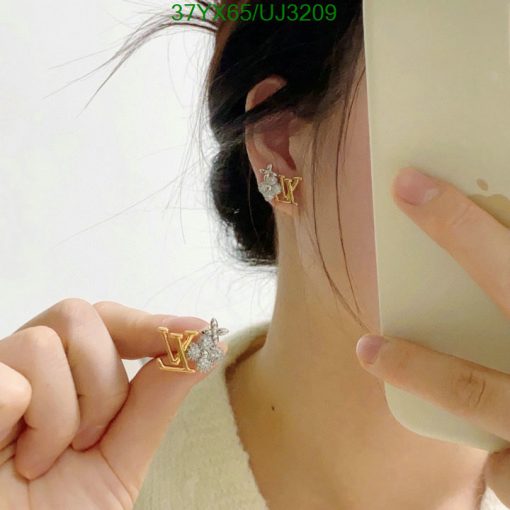 Woman displaying designer monogram earrings.