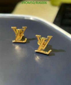 Gold-toned logo earrings on blue surface.