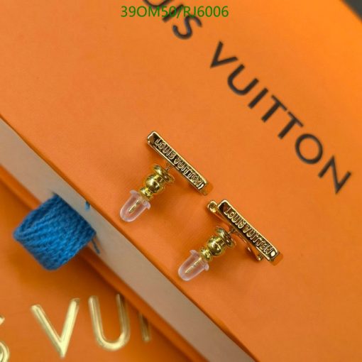 Louis Vuitton earrings on orange background.