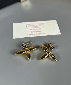 Louis Vuitton gold-tone flower earrings on table.