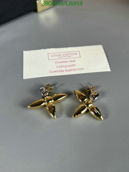 Louis Vuitton gold-tone flower earrings on table.