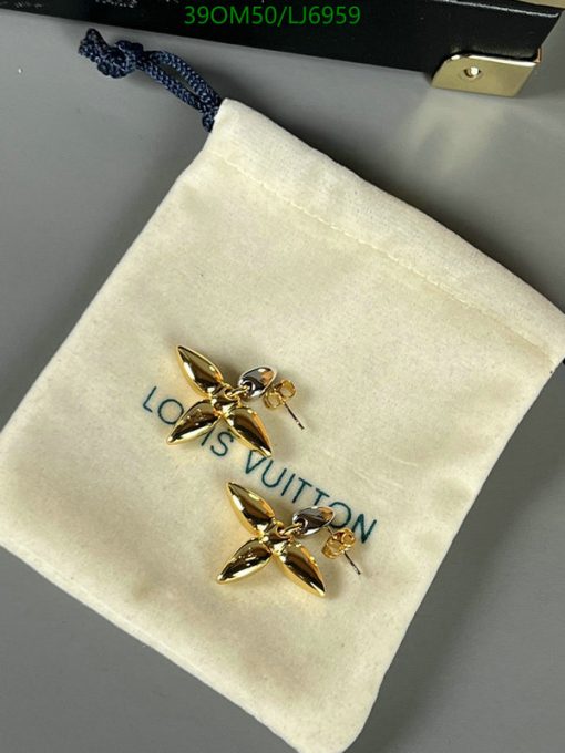 Gold flower-shaped earrings on branded pouch.