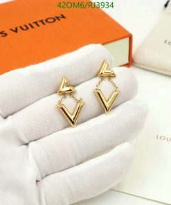 Gold designer logo earrings on white gloves.