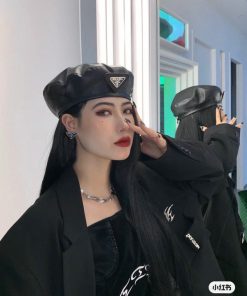 Woman in black leather beret and stylish jacket posing.