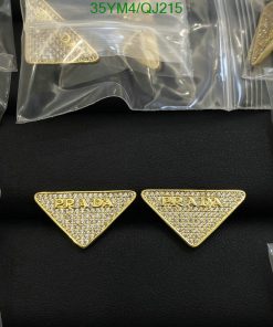 Gold triangular designer earrings with crystals on black background.